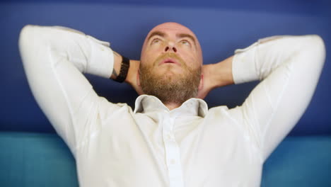 a man leaning back and relaxing at home on a sofa couch