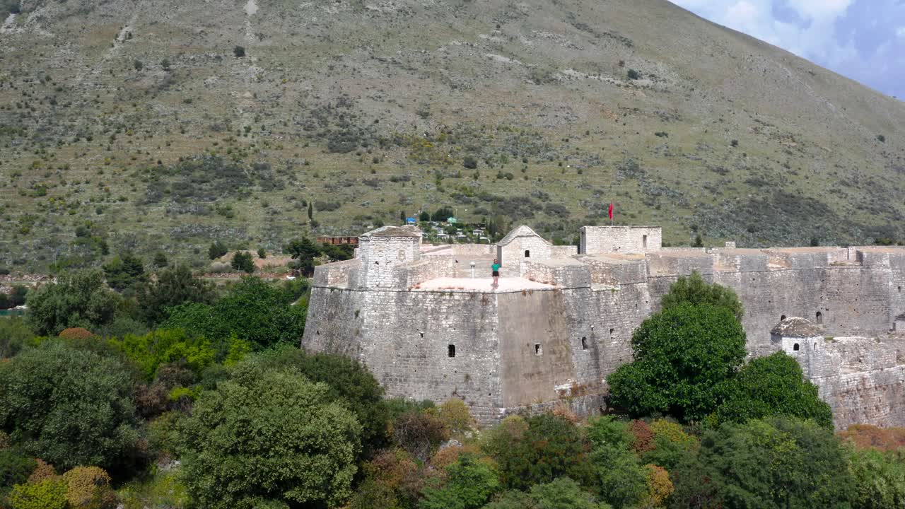vista aérea de una persona de pie en la parte superior del castillo de ali pasha en la bahía de porto palermo, albania