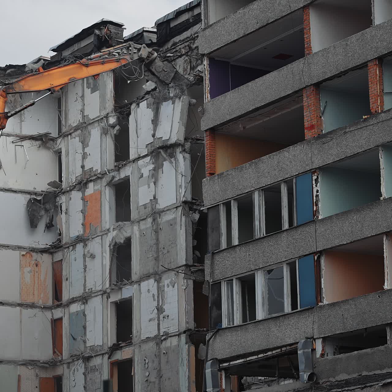 Excavator claw tearing off the big block in the condemned building. Heavy cement block falling down with clouds of dust. Demolition machinery work