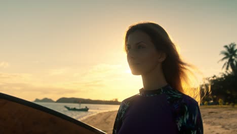 woman with surfboard at sunset beach
