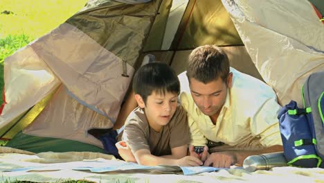 father and son looking at a map lying in a tent