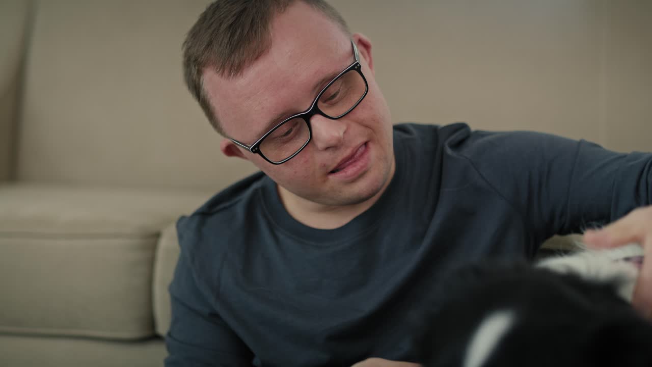 Un homme caucasien avec le syndrome de Down assis sur le sol et jouant avec son chien de compagnie