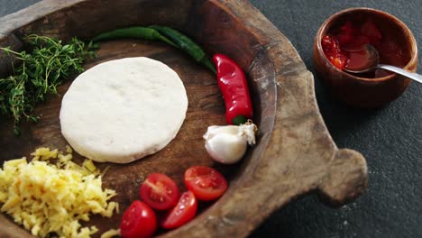 Pizza-dough-with-vegetables-and-spices-on-wooden-tray