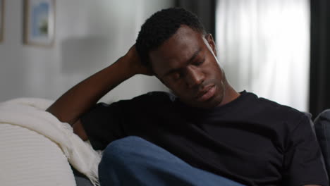 unhappy and depressed young man sitting on sofa at home looking anxious and worried resting head on hand 5