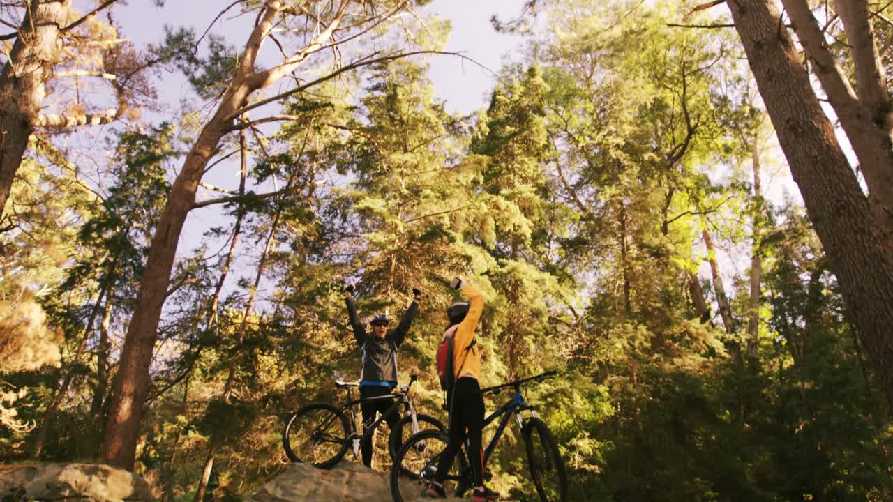 Excited mountain biking couple standing on a rock