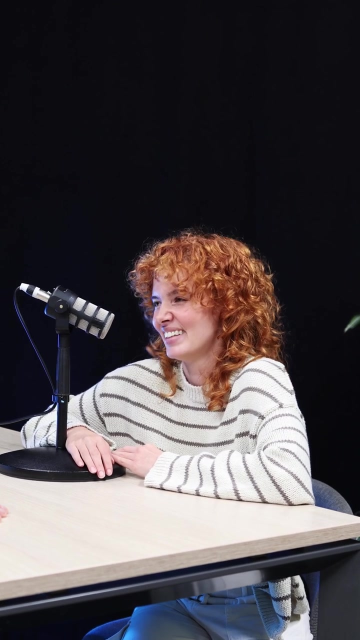 Šťastná mladá žena si povídá a směje se v podcastovém studiu