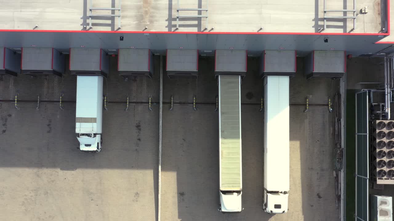 Logistics park with a warehouse - loading hub. Semi-trucks with freight trailers standing at the ramps for loading unloading goods. Aerial