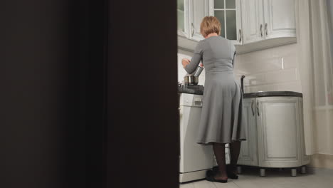 woman seen from behind dancing and cooking in modern kitchen with a relaxed, joyful vibe, she stirs pot and moves with rhythm in stylish, well-lit kitchen
