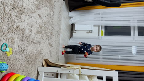 active happy toddler running by the room in one sock. kid holds another sock in hands and shoves it to mouth. vertical screen.