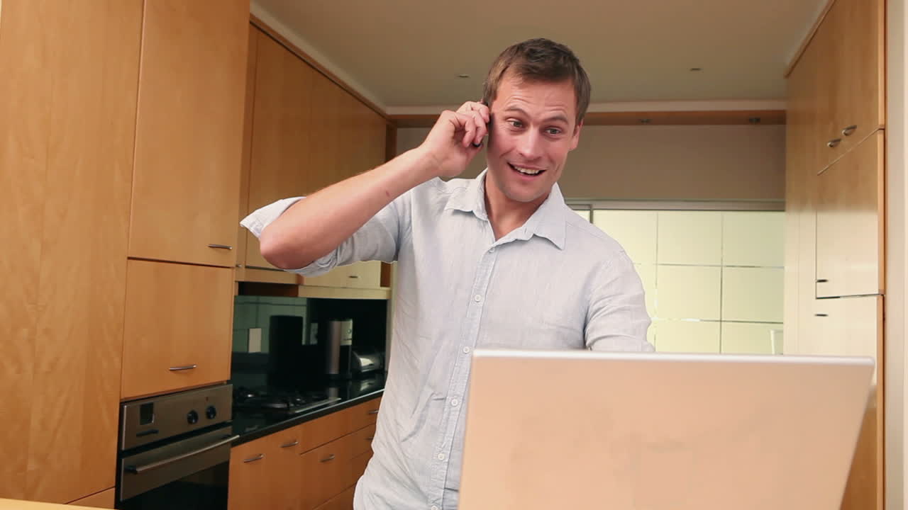 uomo al telefono mentre usa un portatile