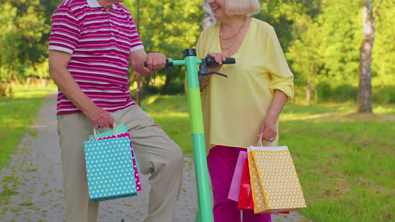 나이 든 세련된 커플 할머니, 할아버지가 스쿠터를 타고 가방과 함께 쇼핑을 한 후