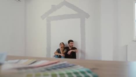 una pareja caucásica descansando después de pintar la pared de la nueva casa.