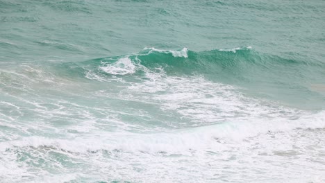 dynamic ocean waves crash against the shore at port campbell, captured in natural lighting with a serene, rhythmic flow