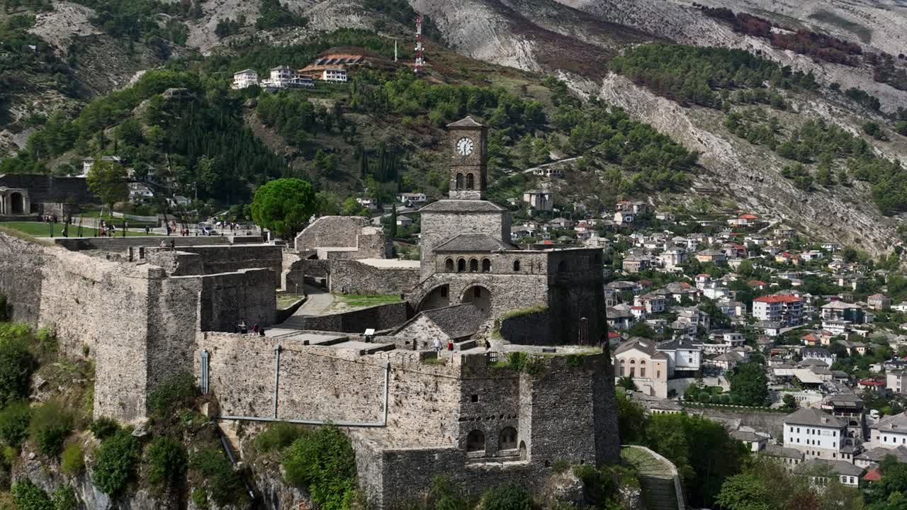 View of Gjirokastër Castle’s historic walls with the charming stone-built village and huge mountains behind.