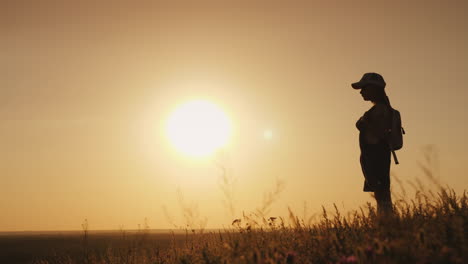 a girl with a backpack is in a picturesque place looking forward to the sunset a little traveler and