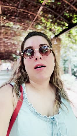 smiling tourist vlogging under green canopy in athens park