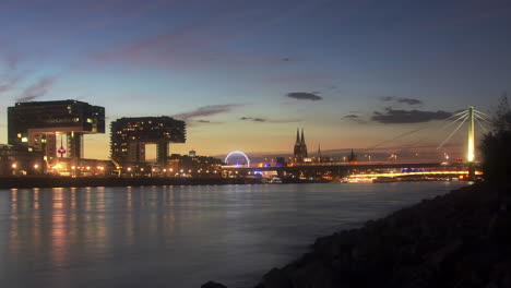 colorful day to night timelapse of colognes crane houses and rhine river in the foreground