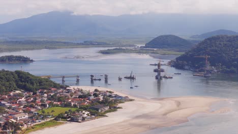 distanced panorama aerial view of the new working project of guaratuba-caiobá bridge, south america, paraná, brazil