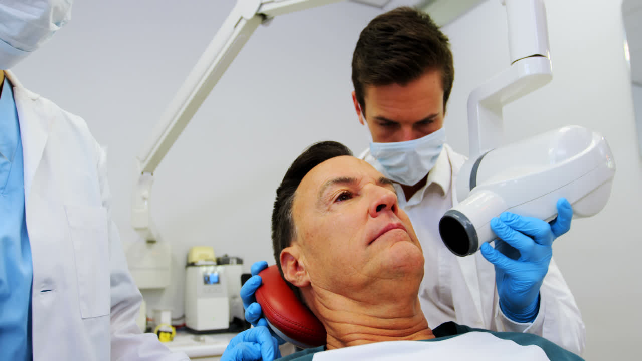 Dentista che esamina un paziente maschio con lo strumento dentale