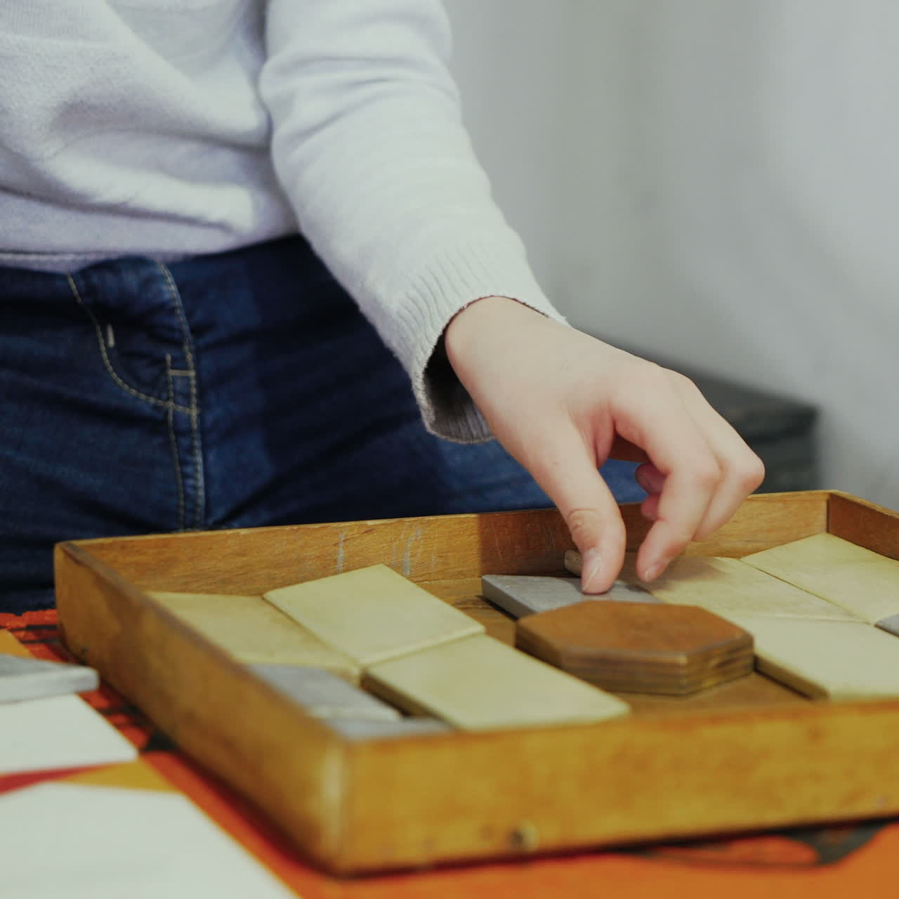 Close-up, hands of a child playing with wooden bricks on a table. Boy with a wooden puzzle. Concept of education. Square video