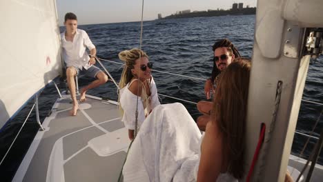 a company of young happy friends sail on a yacht bow on a summer day, friends share interesting stories about their life style with each other, men and women relax in the sun. high angle view from the sail