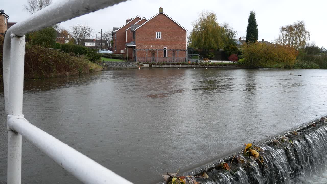 British waterside houses on rainy flowing canal overflow scenic waterway dolly right