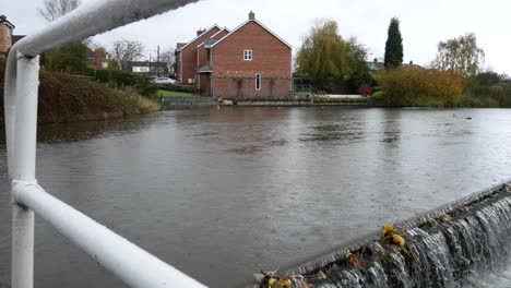 British-waterside-houses-on-rainy-flowing-canal-overflow-scenic-waterway-dolly-right