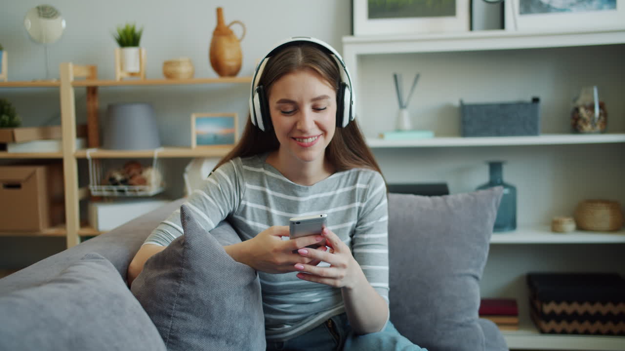 Donna che ascolta musica e usa il telefono sul divano