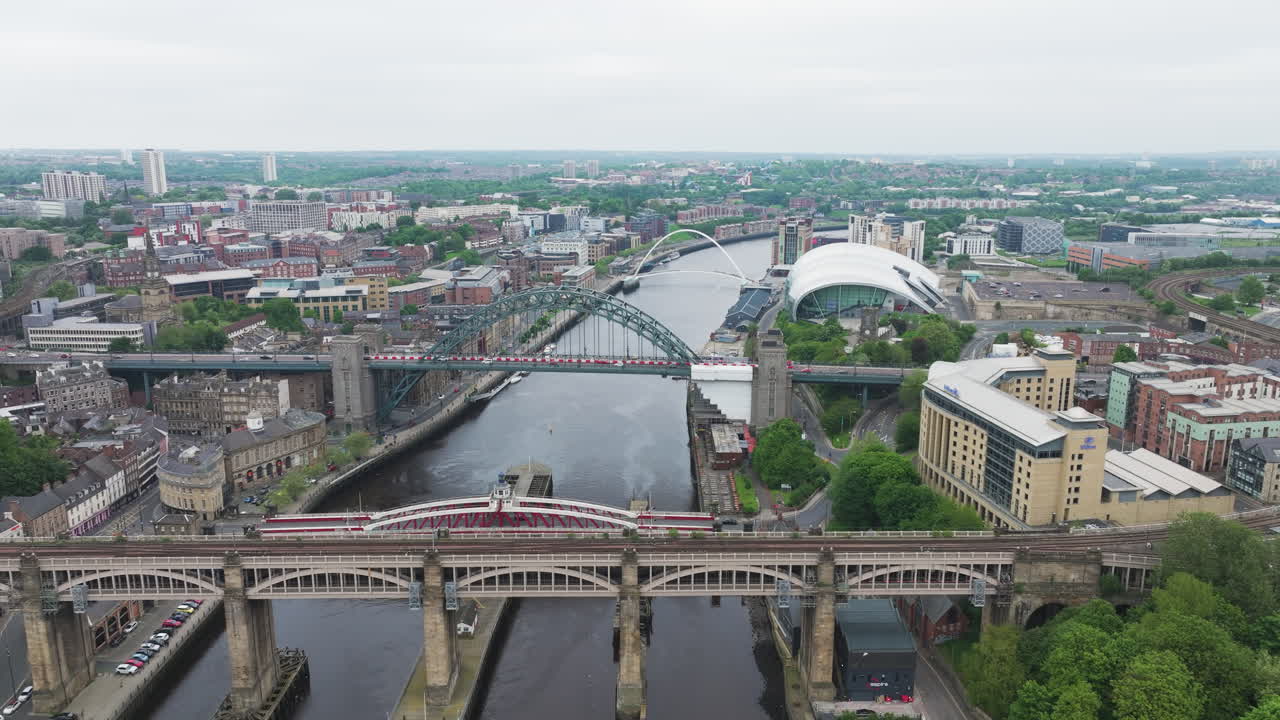 뉴캐슬 어폰 타인 (newcastle upon tyne) 은 구름이 많은 날에 다리와 도시 풍경을 보여주는 항공 사진입니다.