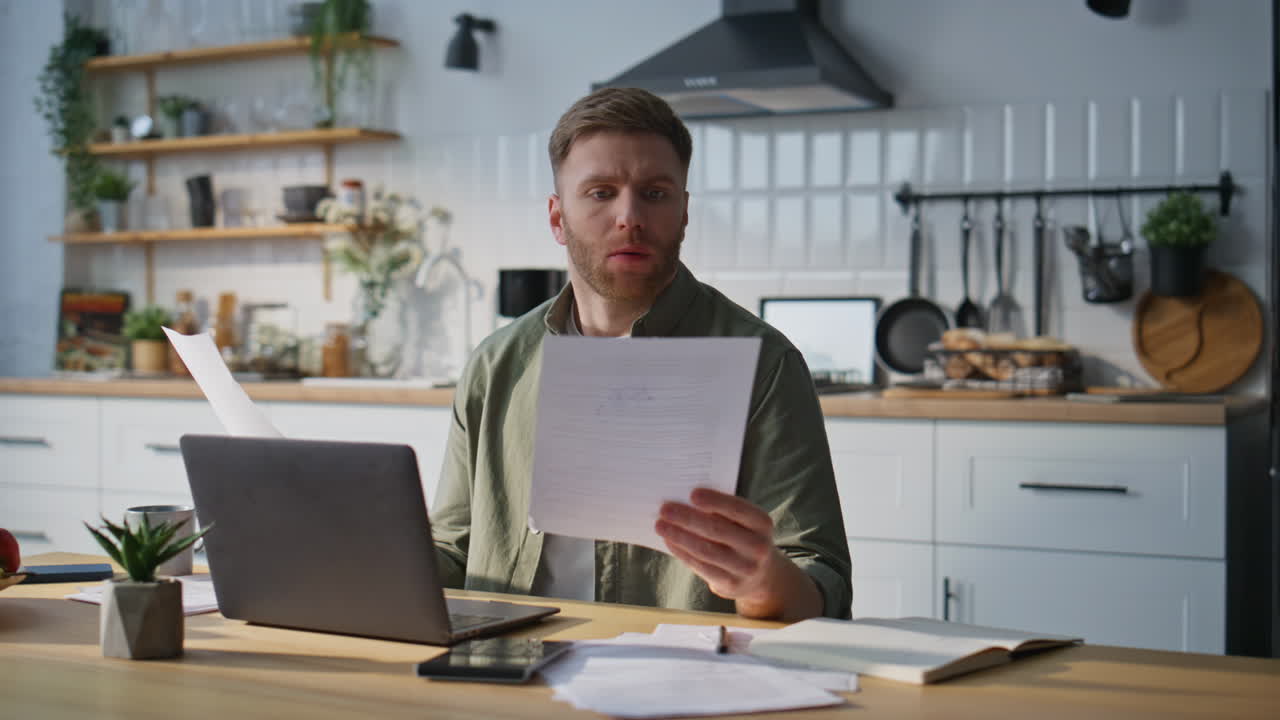 Fokusert profesjonell lesing av dokumenter på hjemmekontoret. Skjeggete frilanser analyserer