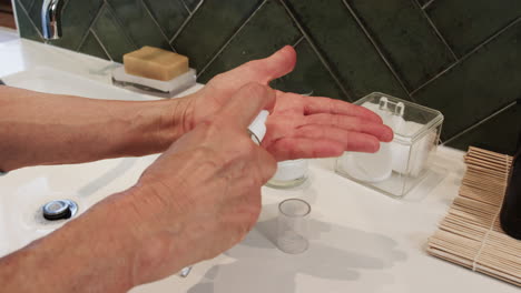 senior woman applying moisturizer on hands in bathroom, focusing on skincare routine, at home