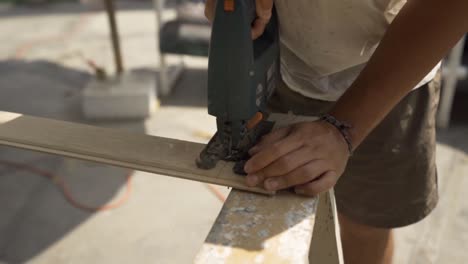 male carpenter cutting wood with jigsaw