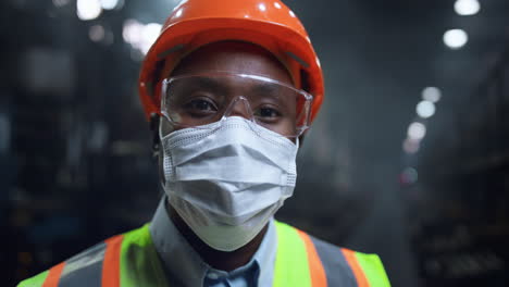 masked supervisor looking camera at huge energy manufacturing special factory.