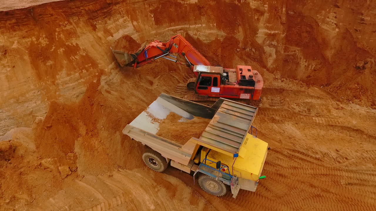 Excavator pouring sand in mining truck at quarry. Excavator loading dump truck