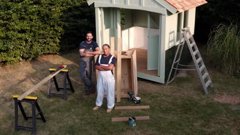 Drone-Portrait-Shot-Of-Carpenters-Building-Outdoor-Summerhouse-In-Garden