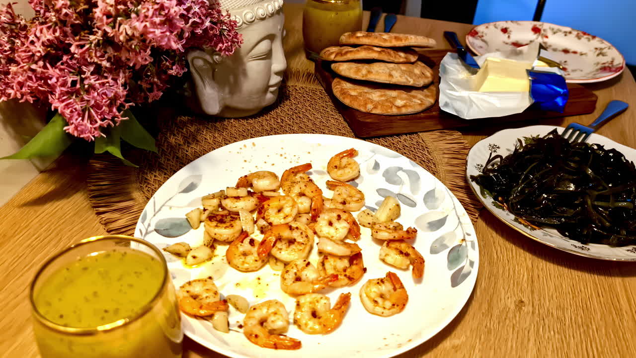 Shrimp dinner with bread, butter, salad and flowers on wooden table