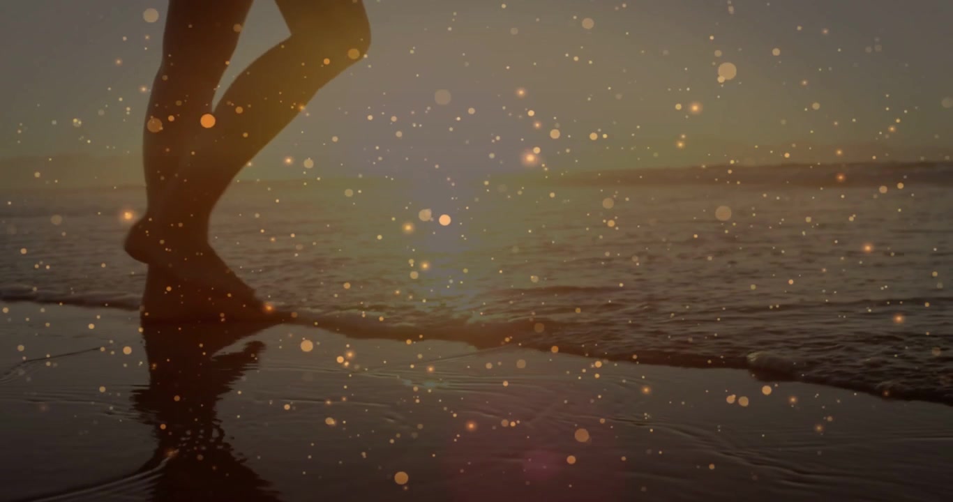 Woman walking shore sunset stepping into surf causing ripples as bokeh sparkling over feet, travel
