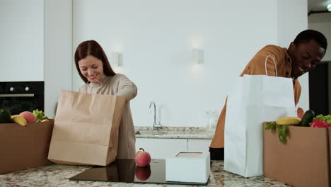 una pareja desempaquetando comestibles.
