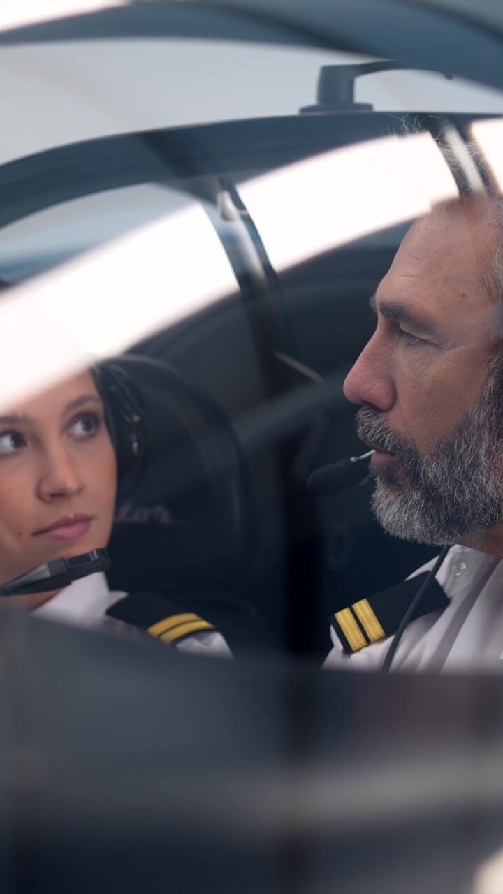 Pilota esperto che istruisce una giovane donna nella cabina di pilotaggio di un aereo