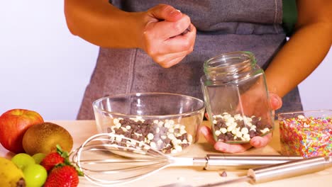 manos transfiriendo fichas de chocolate en un cuenco