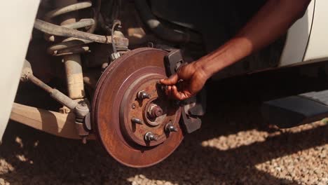 a hand places a lug nut on the car's wheel rotor and tightens it with a cross wrench