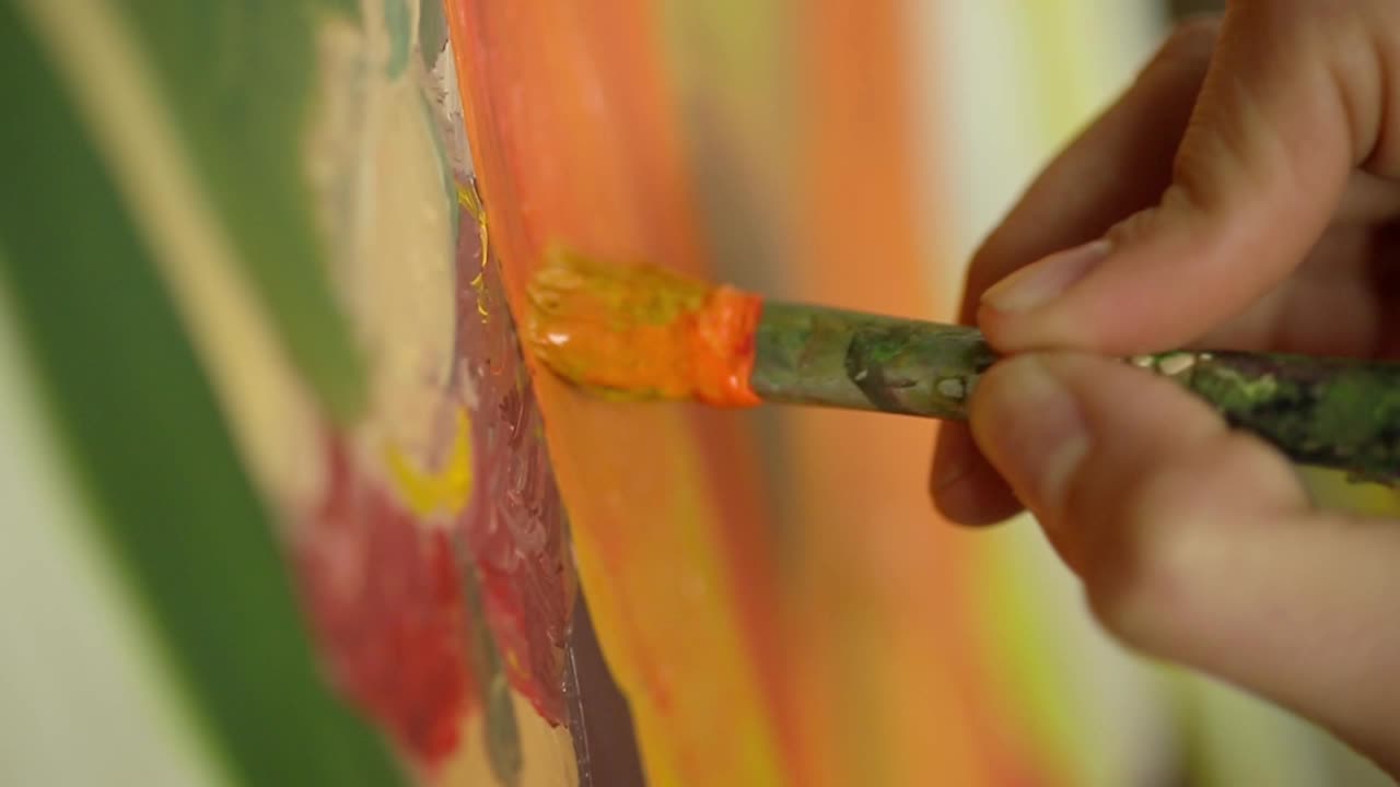 Close-Up of Artist's Hand Painting with a Brush on Canvas