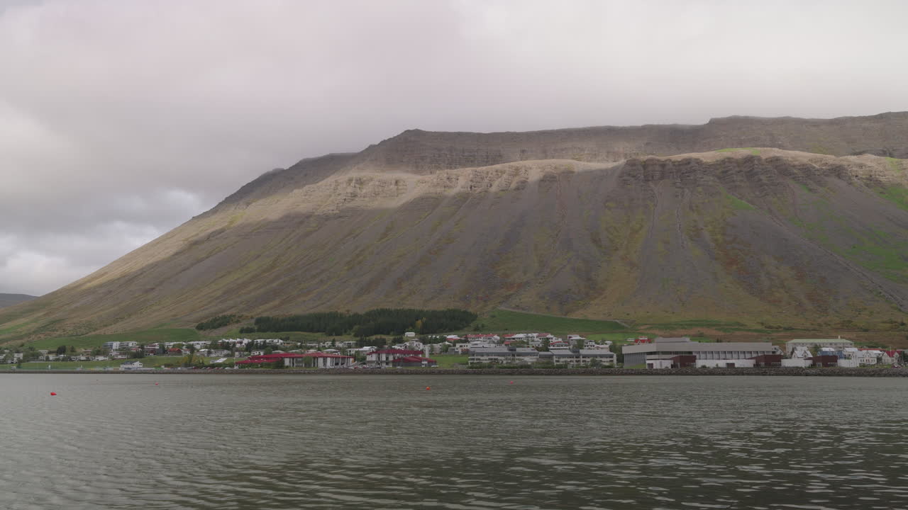 Die Küstenlinie von Ísafjörður, Island, ruhiges Wasser und dichte Wolken über den Bergen