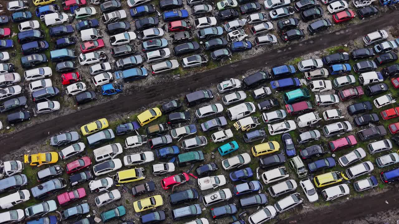 Mange parkerede biler på en losseplads på en skyet dag