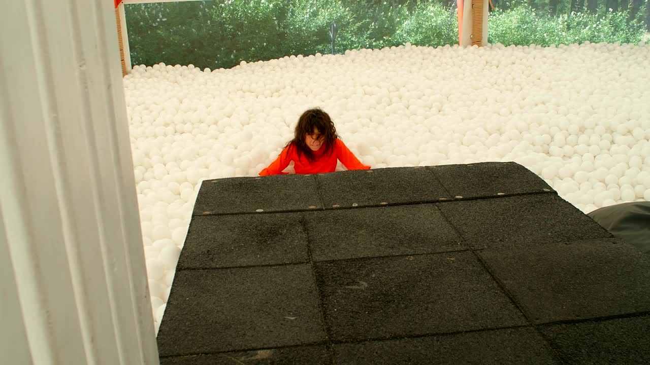 9~10살의 귀여운 소녀가 공 구이에 있는 많은  공들 사이에서 즐거움을 즐기고 있다.