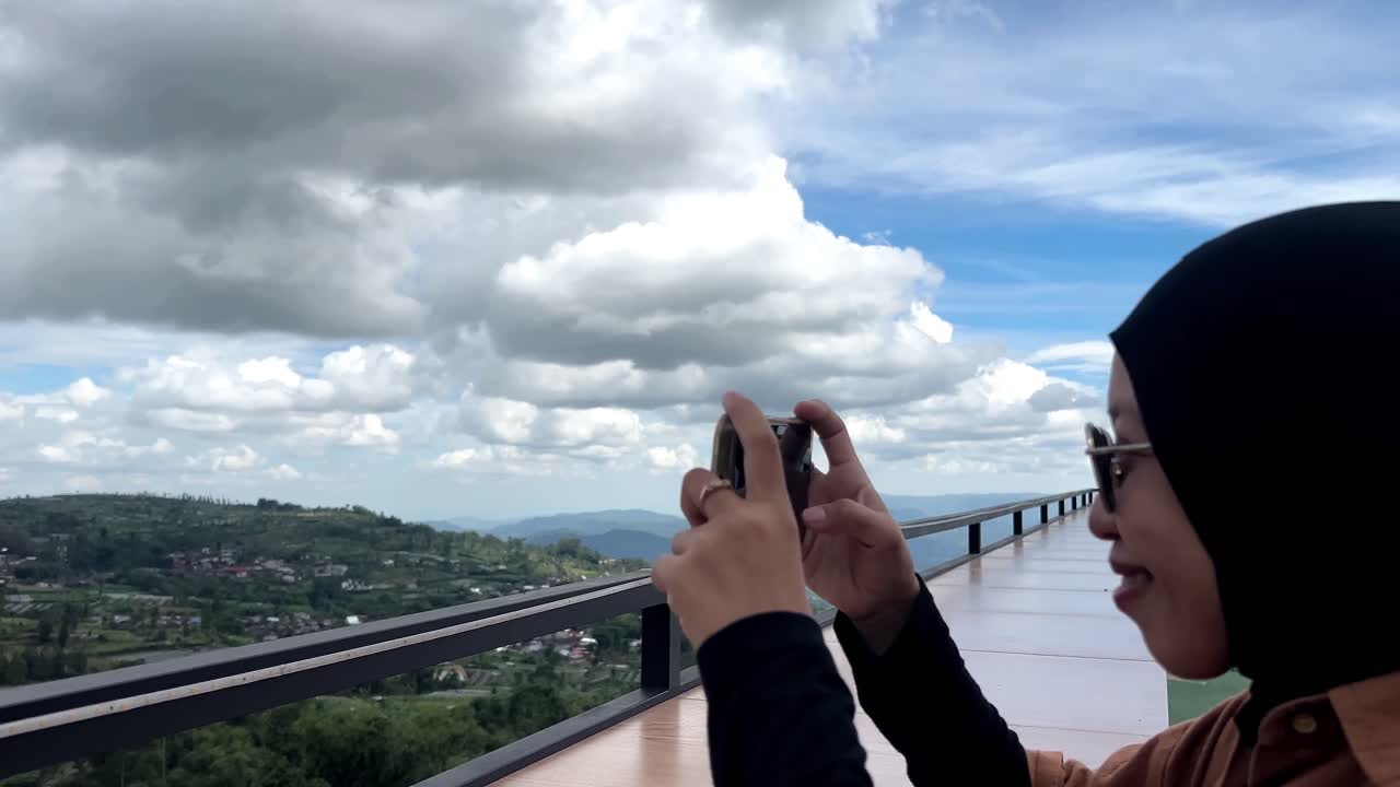 Woman Scrolling A Smartphone With Beautiful Landscape on a mountain rooftop cafe