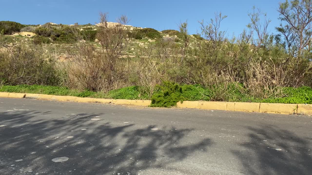 White Racing Car Passes By The Road Track Slowly At The Lush Hill In Imtahleb Malta - Closeup Shot