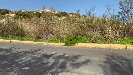 white racing car passes by the road track slowly at the lush hill in imtahleb malta - closeup shot
