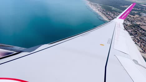 wizzair aircraft wing flying from rome airport over coastline, italy