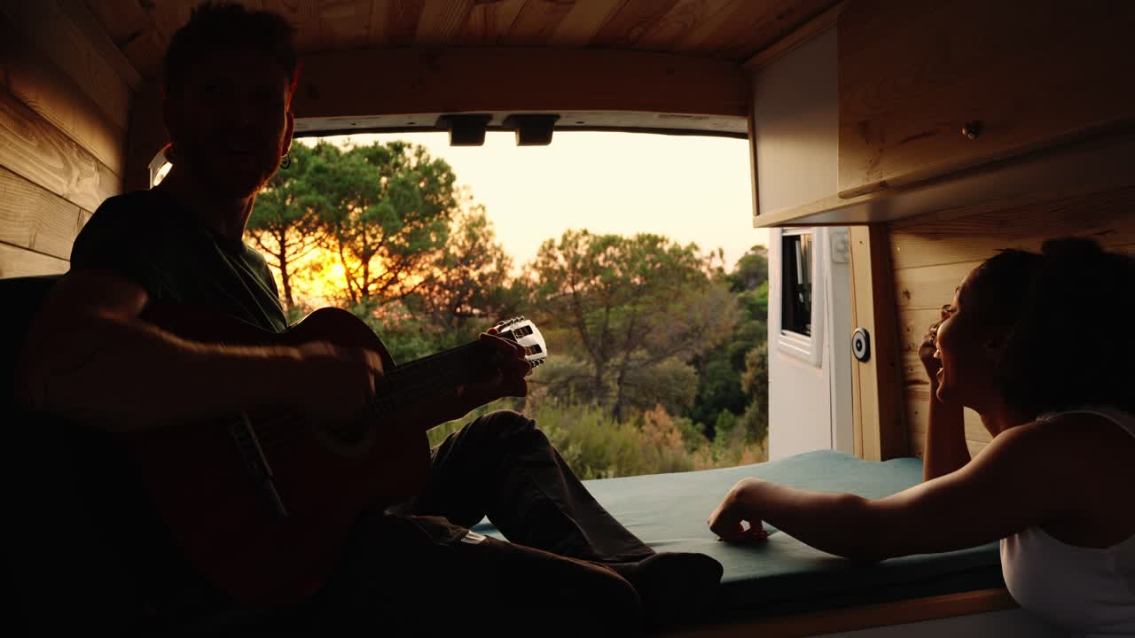 Couple enjoying music in their camper van during a sunset road trip